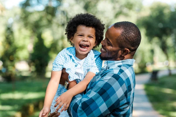 Heureux homme afro-américain tenant dans les bras fils joyeux — Photo de stock