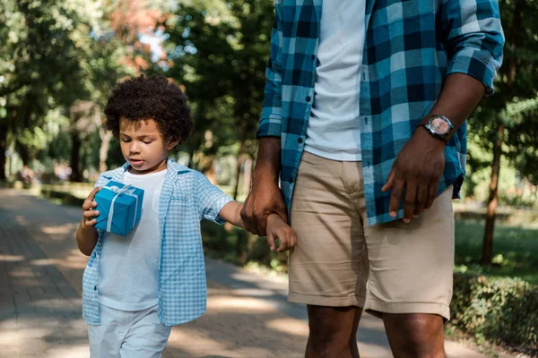 Обрізаний вид на афроамериканця, який тримає руки з милою дитиною, дивлячись в даний час — стокове фото