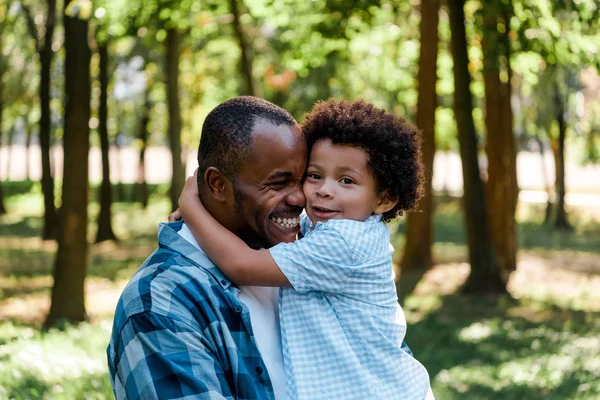 Lindo africano americano niño abrazando feliz padre - foto de stock