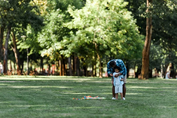 Afrikanisch-amerikanischer Vater steht neben süßem Sohn auf Gras — Stockfoto