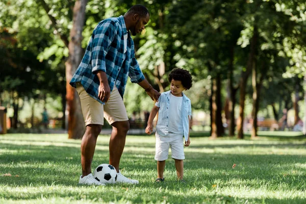 Guapo africano americano padre jugando fútbol con lindo hijo - foto de stock