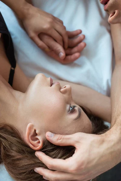 Top view of man touching face of attractive girl while lying on bed — Stock Photo