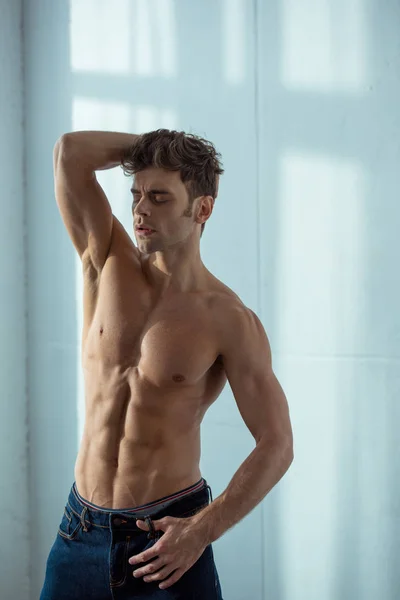 Sexy shirtless man in denim jeans standing in bedroom — Stock Photo