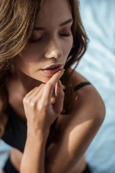 Selective focus of attractive girl touching lips in bedroom — Stock Photo