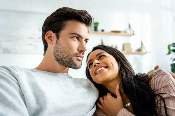 Afroamerikanerin und schöner Mann lächeln und umarmen sich in Wohnung — Stockfoto