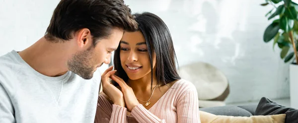 Plan panoramique d'une femme afro-américaine souriante regardant un bel homme dans un appartement — Photo de stock