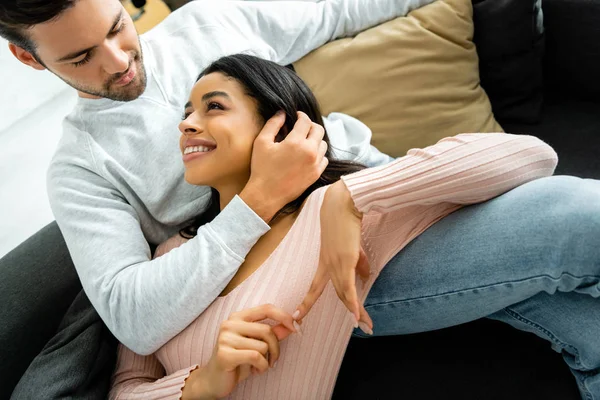 Africano americano mujer y guapo hombre sonriendo y abrazando en apartamento - foto de stock