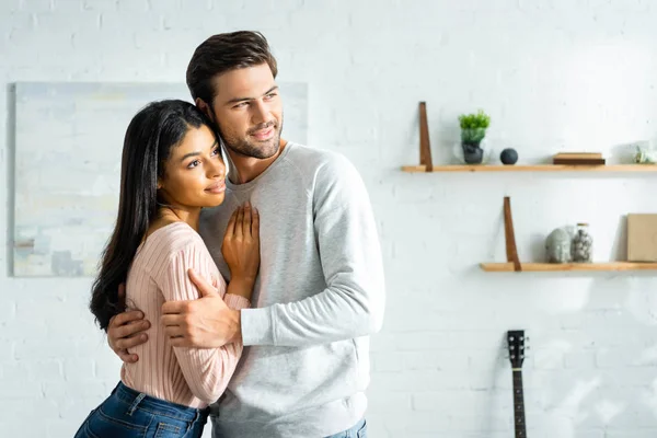 Afro-americano mulher e bonito homem sorrindo e abraçando no apartamento — Fotografia de Stock