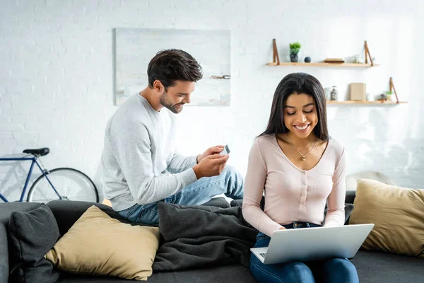 Smiling african american woman using laptop and man holding credit card — Stock Photo