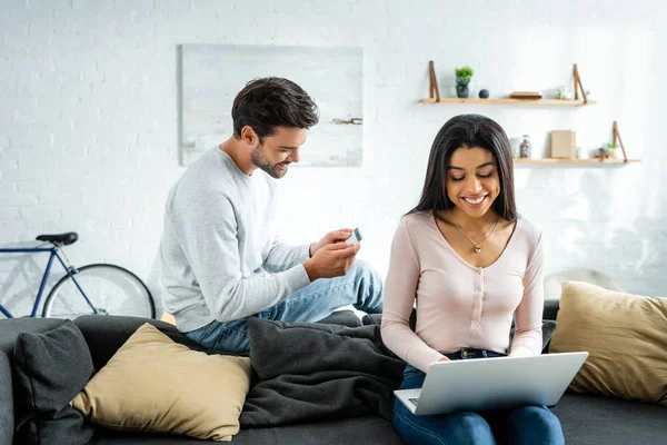 Sorrindo mulher afro-americana usando laptop e homem segurando cartão de crédito — Fotografia de Stock