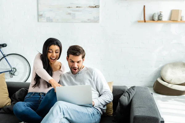 Schockierte afrikanisch-amerikanische Frau und schöner Mann schaut auf Laptop — Stockfoto