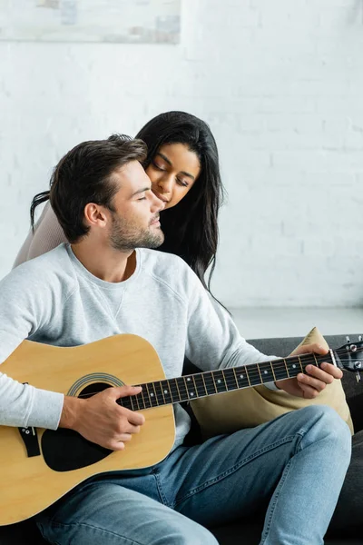 Mujer afroamericana con los ojos cerrados y hombre con guitarra acústica - foto de stock