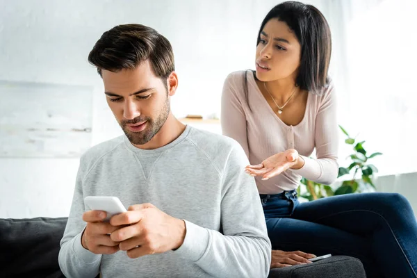 Mujer afroamericana hablando con un hombre guapo usando smartphone - foto de stock