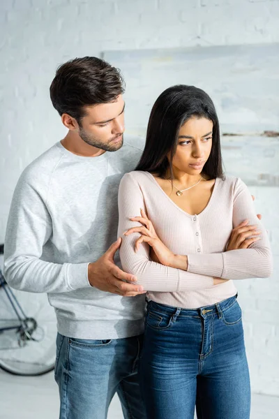 Handsome man hugging sad african american woman with crossed arms — Stock Photo