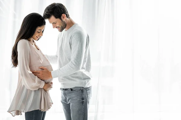 Homem bonito abraçando barriga de sua mulher americana africana grávida — Fotografia de Stock