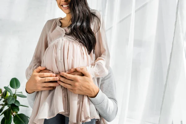 Abgeschnittene Ansicht von Mann umarmt Bauch seiner schwangeren Afroamerikanerin — Stockfoto
