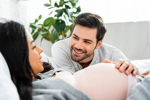 Selective focus of handsome man hugging belly of his pregnant african american woman — Stock Photo