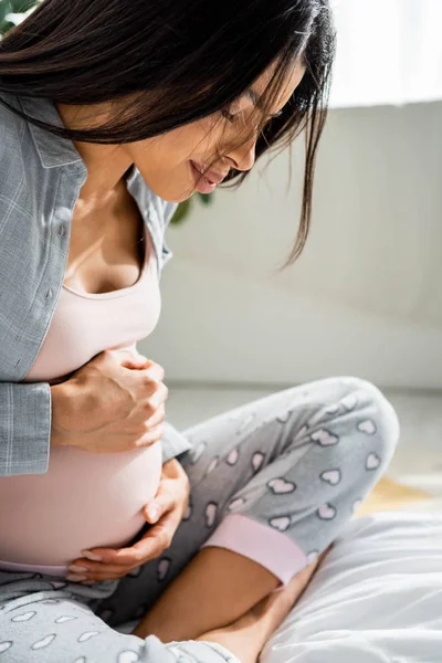 Donna africana americana incinta in pigiama che abbraccia la pancia e prova dolore — Foto stock