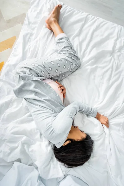 Vista superior da mulher grávida afro-americana em pijama tocando barriga e sentindo dor — Fotografia de Stock