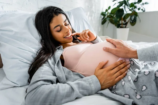 Vue recadrée de l'homme étreignant ventre de sa femme enceinte afro-américaine — Photo de stock