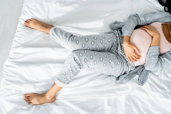 Cropped view of african american pregnant woman in pajamas touching belly and feeling pain — Stock Photo