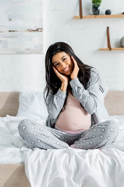 Sonriente africano americano embarazada mujer en pijama mirando cámara - foto de stock