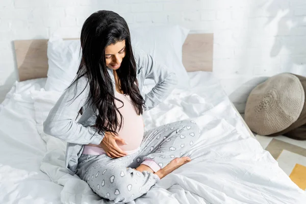 Souriant afro-américain enceinte femme en pyjama étreignant ventre — Photo de stock