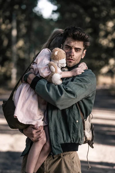 Homme beau et sale tenant dans les bras enfant en tchernobyl, concept post-apocalyptique — Photo de stock