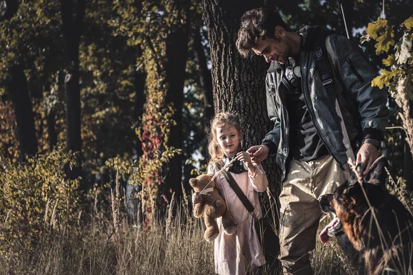 Selective focus of happy man touching kid near german shepherd dog, post apocalyptic concept — Stock Photo