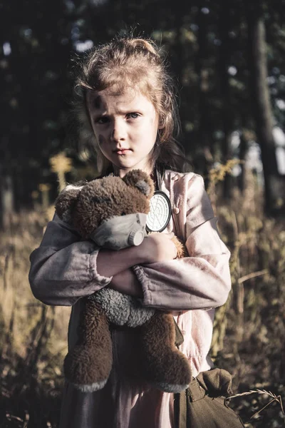 Sad child holding dirty teddy bear in chernobyl, post apocalyptic concept — Stock Photo