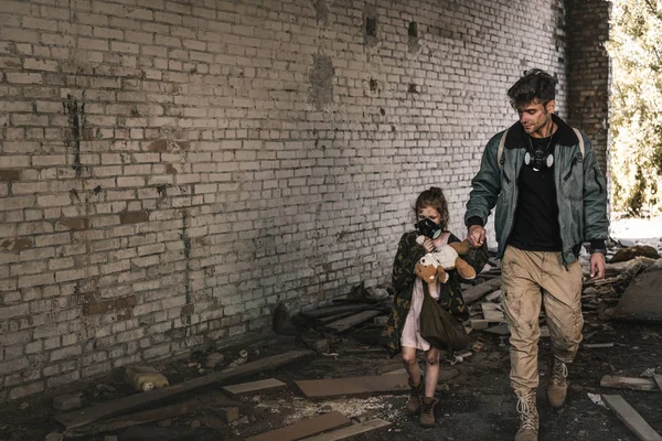 Man holding hands with kid while walking on street in chernobyl, post apocalyptic concept — Stock Photo