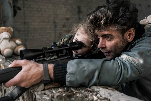 Bel homme touchant pistolet près de l'enfant, concept post apocalyptique — Photo de stock