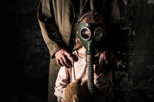 Cropped view of man standing near kid in gas mask, post apocalyptic concept — Stock Photo