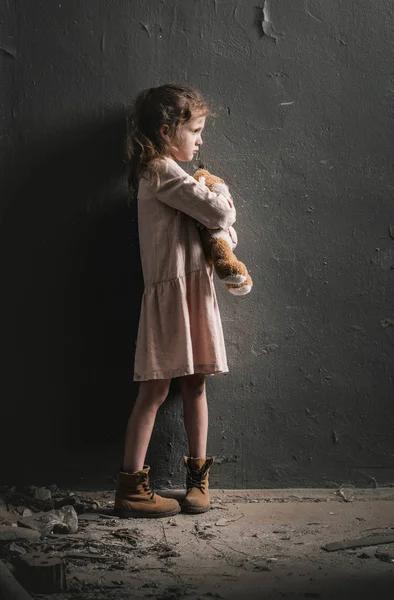 Side view of kid holding soft toy near wall, post apocalyptic concept — Stock Photo