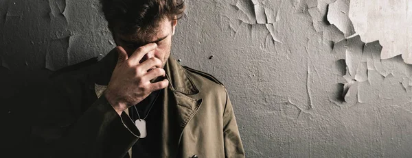 Panoramic shot of man touching face while standing near wall, post apocalyptic concept — Stock Photo