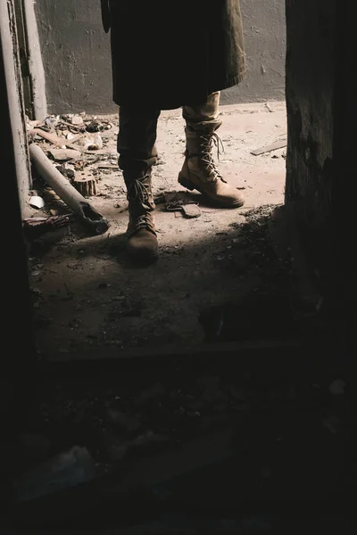 Cropped view of man in boots standing in old room, post apocalyptic concept — Stock Photo