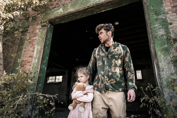 Handsome man standing with kid outside, post apocalyptic concept — Stock Photo