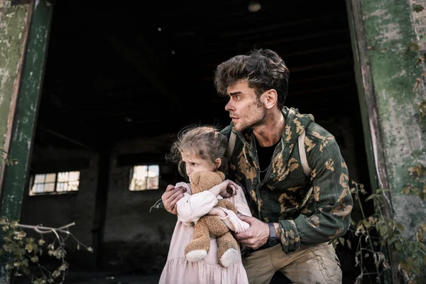 Handsome man standing with cute child outside, post apocalyptic concept — Stock Photo