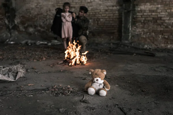 Foyer sélectif de l'ours en peluche près de l'homme et l'enfant dans la construction, concept post-apocalyptique — Photo de stock