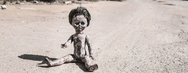 Panoramic shot of old and scary baby doll on ground, post apocalyptic concept — Stock Photo