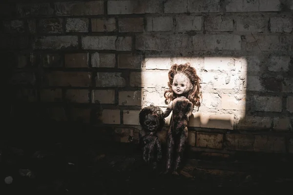 Luz do sol em bonecas velhas e assustadoras perto da parede de tijolos, conceito pós-apocalíptico — Fotografia de Stock