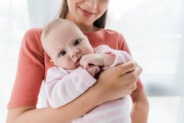 Vue recadrée de femme heureuse tenant dans les bras adorable petite fille — Photo de stock