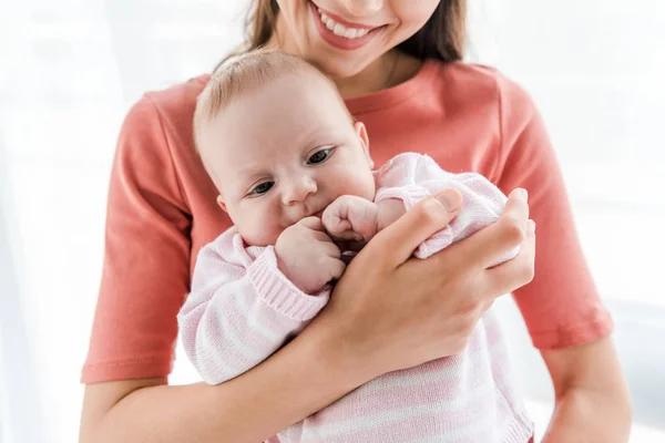 Cropped view of cheerful mother holding in arms adorable infant daughter at home — Stock Photo