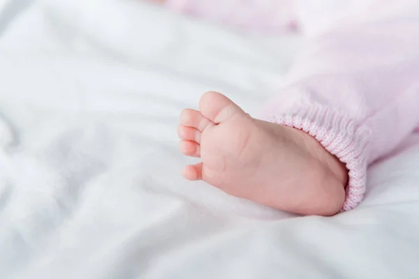 Cropped view of small barefoot of infant baby lying on bed — Stock Photo