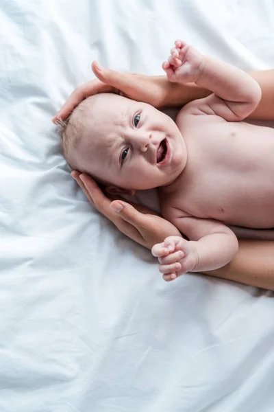 Vue de dessus de la mère touchant bébé pleurant dans la chambre — Photo de stock