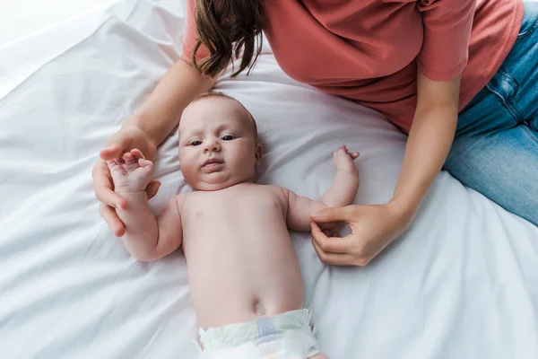 Vista superior de la madre tocando lindo bebé en el dormitorio - foto de stock