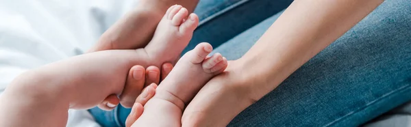 Plano panorámico de la madre tocando las piernas del bebé en casa - foto de stock