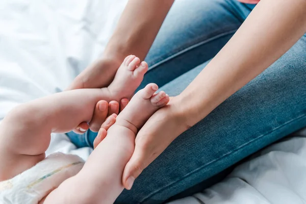 Обрізаний вид матері торкається ніг немовляти дочки вдома — стокове фото