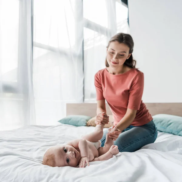 Messa a fuoco selettiva del bambino carino guardando la fotocamera vicino alla madre — Stock Photo