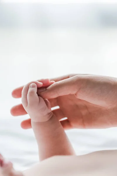 Vue recadrée de la femme faisant massage tout en touchant la main du bébé — Photo de stock